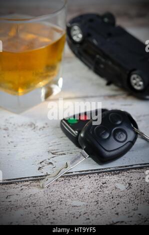 Car keys, glass of whiskey in background. Drinking and driving