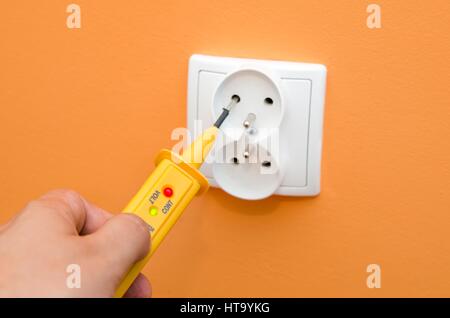 Electricity current meter, turn-screw into the socket on orange wall. Stock Photo