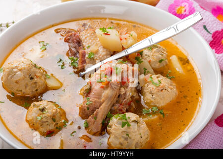 Soup with meatballs and chicken meat in white bowl with herbs Stock Photo