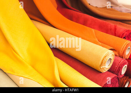 Colorful rolls of natural linen cloth lie on the market counter Stock Photo