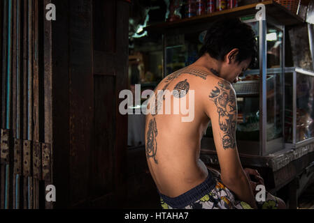 A tattooed man lost in thought in Khlong Thoey, Bangkok, Thailand. Stock Photo