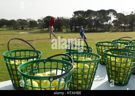 Golfers on practice range at dawn Stock Photo