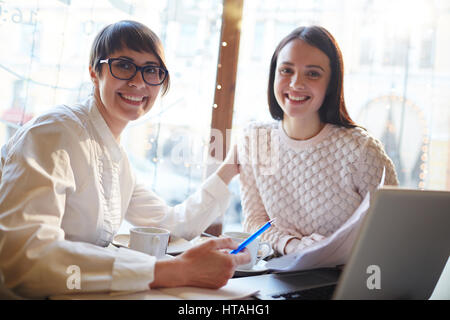 Small group of successful businesswomen having meeting or appointment in cafe Stock Photo