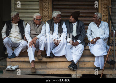 A gathering of minds in Jaisalmer, India: middle-aged and elderly men conversing with each other on street-side steps. Stock Photo