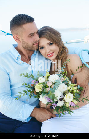 Young woman with flowers looking at camera with smile while her husband embracing her Stock Photo