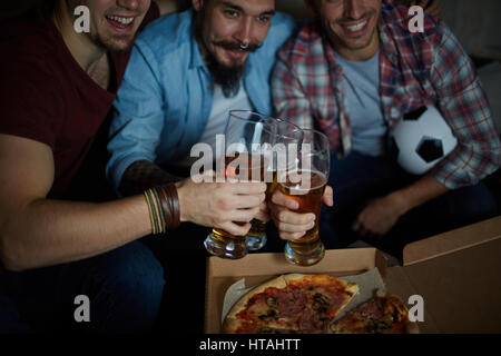 Happy friends with glasses of beer and pizza watching television Stock Photo