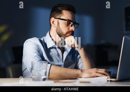 Serious man with laptop concentrating on work late in the evening Stock Photo