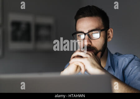 Pensive analyst reading information in the net Stock Photo