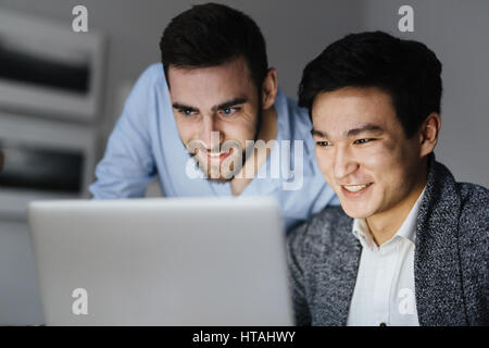 Creative men reading data in laptop with smiles Stock Photo