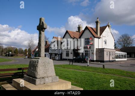War Memorial, Swaffham Bulbeck, Cambridgeshire, and the Black Horse inn which, proclaims on its walls ‘Drink – Eat - Sleep’ Stock Photo
