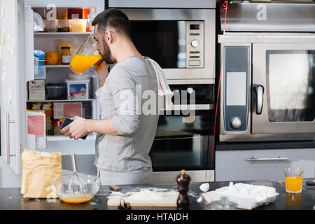 Thirsty man drinking juice from jug in the kitchen Stock Photo