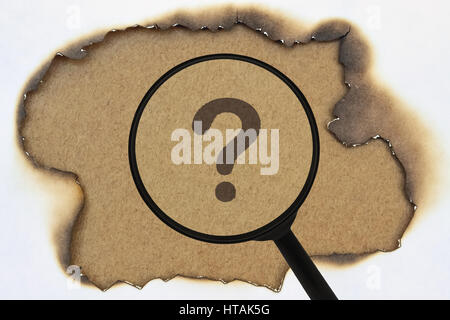 Question mark under a magnifier on burnt yellow paper Stock Photo