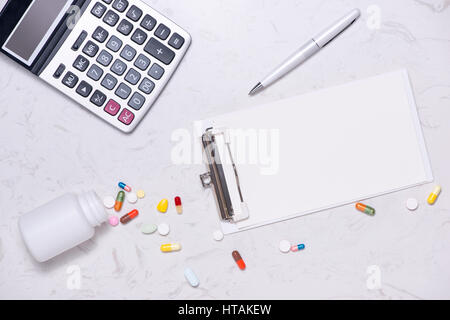 Healthcare costs concept. Opened medicine bottle and spilled out capsules on table. Stock Photo