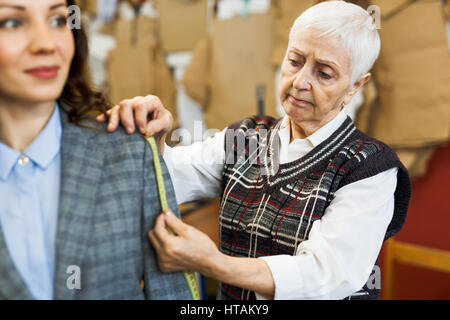 Clothing designer taking measures from her client Stock Photo