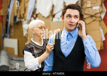 Client of dressmaker talking on cellphone in tailoring-shop Stock Photo