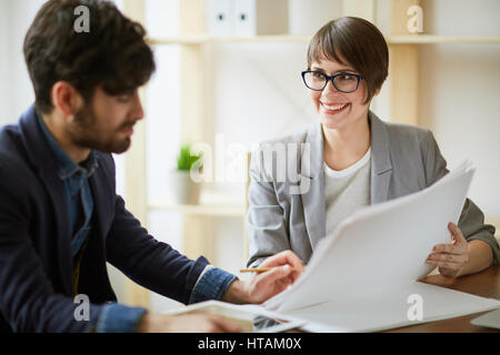 Portrait of two smiling colleagues making final decisions  discussing working plans and documentation in modern office Stock Photo