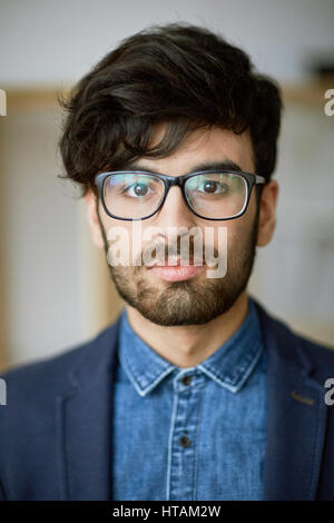 Head and shoulders portrait of successful young business expert wearing creative haircut and glasses looking confidently to camera Stock Photo