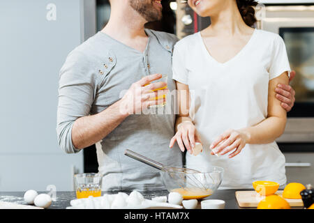 Young man embracing his wife while cooking breakfast in the kitchen Stock Photo