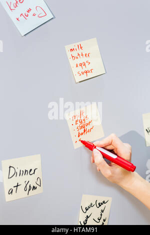Woman writing lists of products to buy on notepaper Stock Photo