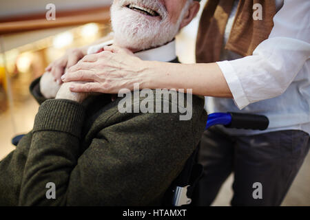 Smiling aged man in wheelchair and his caregiver Stock Photo