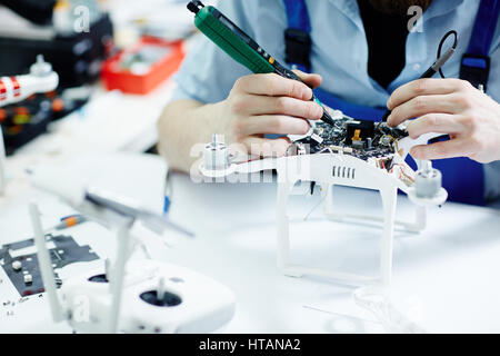 Closeup shot of unrecognizable service worker testing electric current in circuit board of disassembled drone using multimeter tool on table in mainte Stock Photo