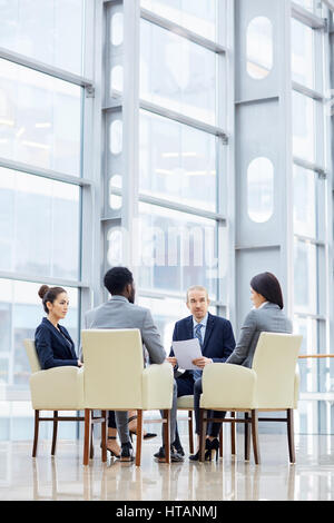 Business people gathered at briefing to discuss financial documents Stock Photo