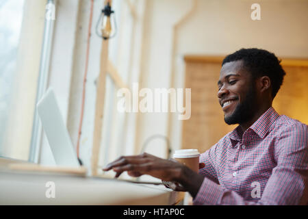 Young designer with drink, browsing in the internet Stock Photo