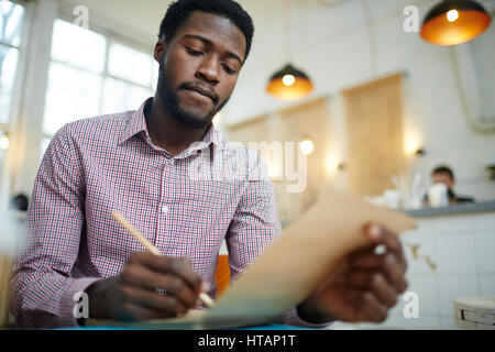 Young designer making notes in his notepad Stock Photo
