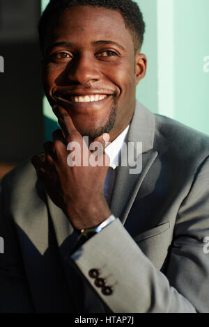 Portrait of successful young African-American businessman standing in bright sunlight and smiling happily Stock Photo