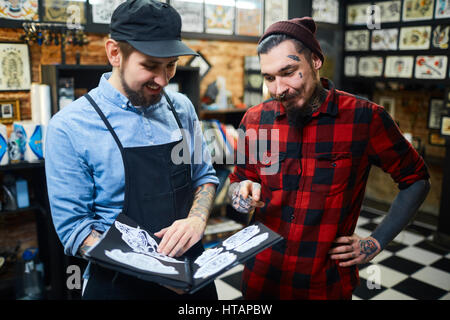 Master of tattoo helping his client to choose ornament Stock Photo