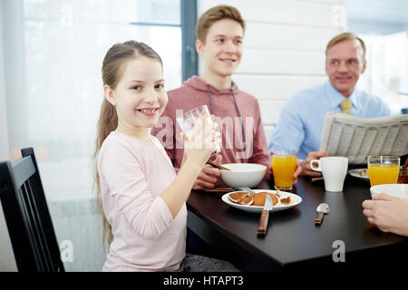 Happy girl drinking milk and eating pancakes for breakfast Stock Photo