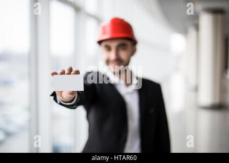 Construction worker holding blank business card, in building construction. Stock Photo