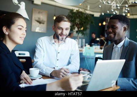 Group of young economists discussing online statistics Stock Photo
