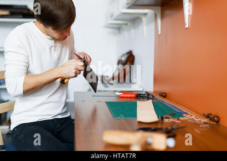 Tanner making leather wallet by workplace Stock Photo
