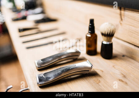 Electric razors, shaving brush and spray bottle on wooden table Stock Photo