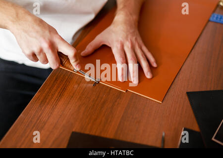 Man using special knife or cutter while processing leather workpiece Stock Photo