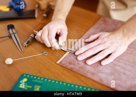 Hands of upholsterer processing leather workpiece Stock Photo