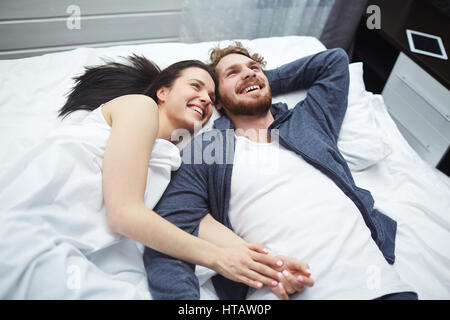 Joyful young couple relaxing in bed Stock Photo