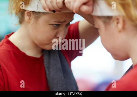 Portrait of young overweight woman looking in mirror, upset and dissatisfied with her body image Stock Photo