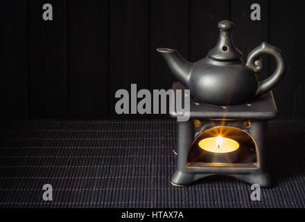 Candle driven aroma lamp diffuse essential oils for Aromatherapy or Esoterics. Dark background, Black on black colors Stock Photo