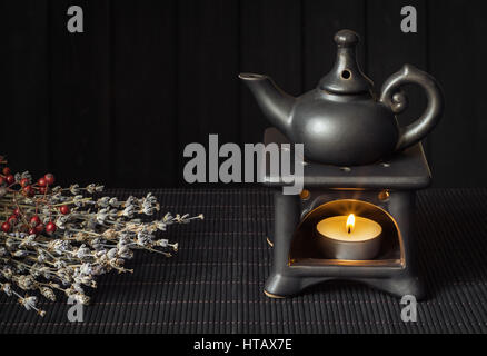 Candle driven aroma lamp diffuse essential oils for Aromatherapy or Esoterics. Dark background, Black on black colors Stock Photo
