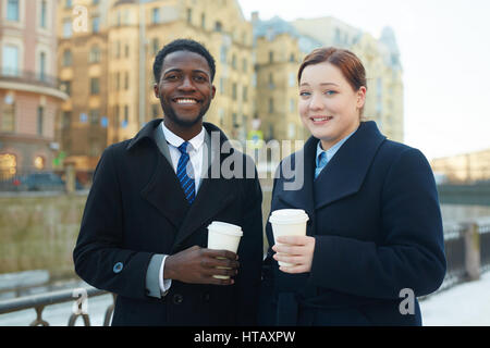 Portrait of two business colleagues leaving office and standing in autumn street by river Stock Photo