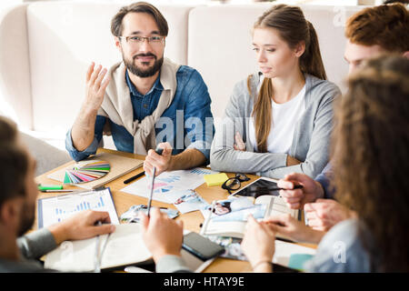 Company of young designers having discussion at meeting Stock Photo