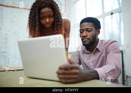 Small group of managers looking at financial analysis on laptop display Stock Photo