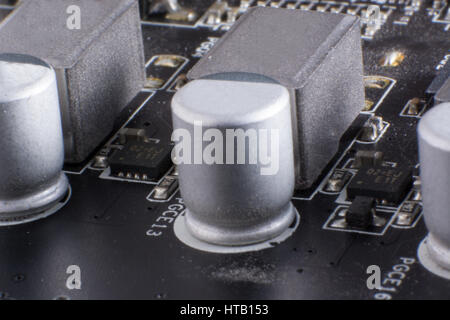 A dusty computer components. Detail of a dusty computer mainboard. Electrolytic capacitors visible on the printed circuit board. Selective focus Stock Photo