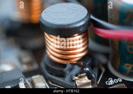 A dusty computer components. Detail of a dusty computer mainboard. Electrolytic capacitor  and conductor visible on the printed circuit board. Selecti Stock Photo