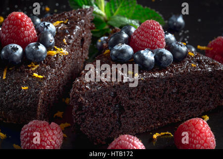 Slices of homemade chocolate cake decorated with raspberries and blueberries. Stock Photo