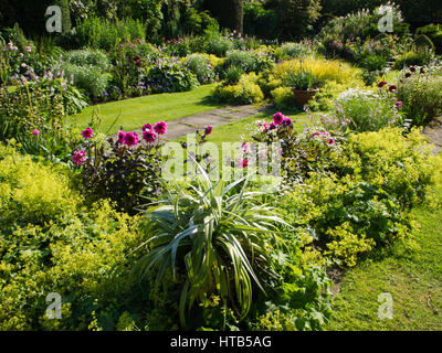 Chenies Manor sunken garden, Buckinghamshire. Evening sun enhanced the colours of foliage, Lady's Mantle and dark pink dahlias adding to their beauty. Stock Photo