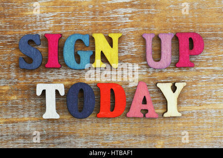 Sign up today written with colorful letters on rustic wooden surface Stock Photo