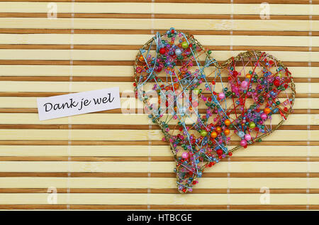 Dank je wel (thank you in Dutch) with heart made of colorful beads on bamboo mat Stock Photo